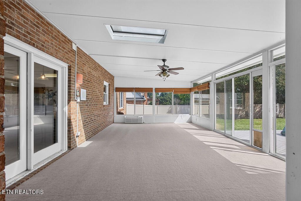Long sunroom with a wall of windows, a skylight and a ceiling fan at 12736 Broken Saddle Rd