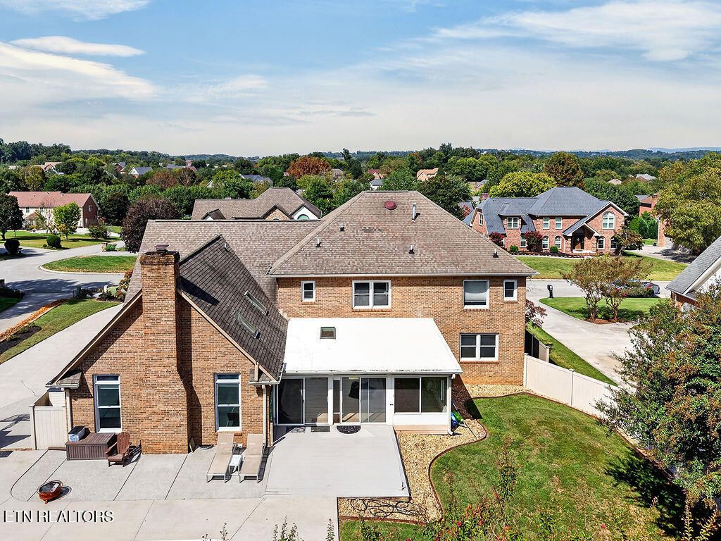 Aerial view of the back of the all-brick home at 12736 Broken Saddle Rd, showing the sunroom, patio and the surrounding west Knox County neighborhood