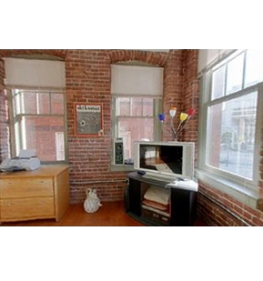 Brick-and-beam interior with a window-side desk in the original 26 Stillman guide