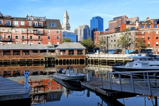 Boston waterfront with brick buildings, moored boats and a city skyline