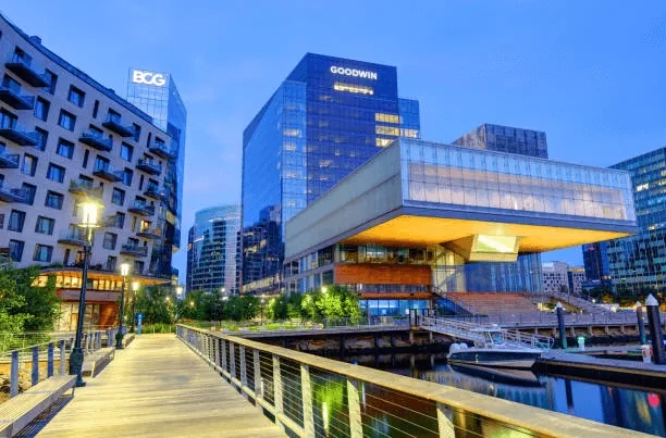 A waterfront walkway beside contemporary Seaport buildings at dusk