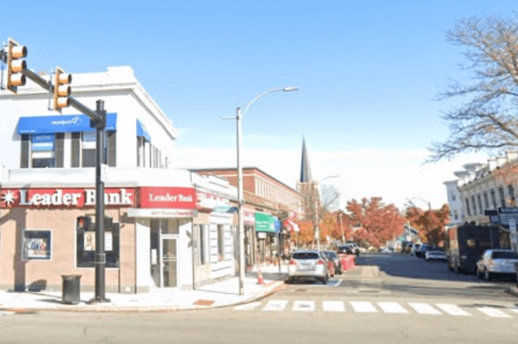 Storefronts and parked cars beside a marked pedestrian crossing.