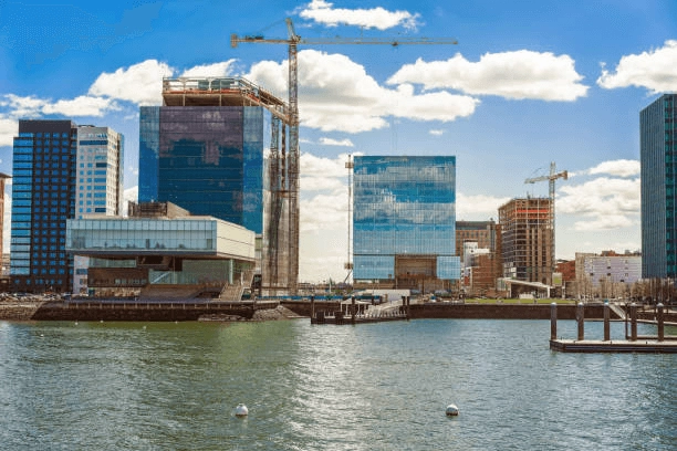 Waterfront buildings and construction cranes viewed across water.