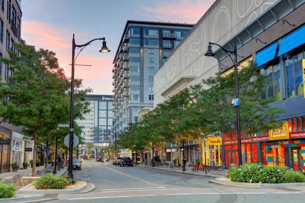 Tree-lined street with shops and apartment buildings at dusk