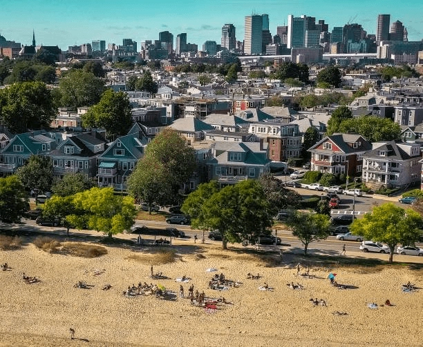 Beach, homes and trees with a distant city skyline