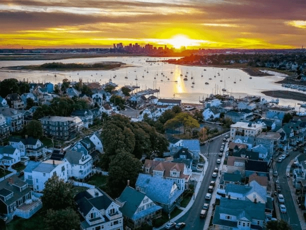 Homes beside a waterway with sailboats at sunset