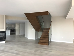 Empty interior with wood flooring, staircase and glass railing.
