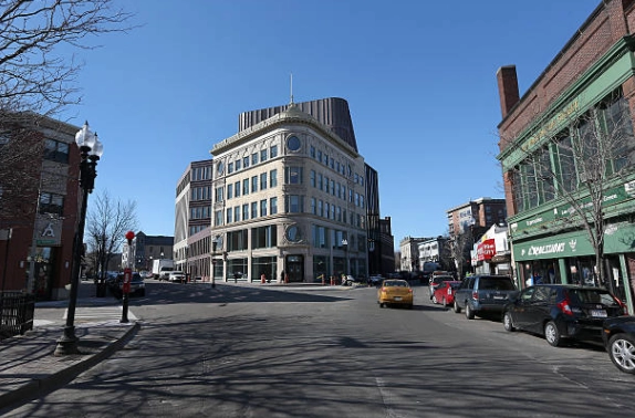 Street junction with a rounded corner building and storefronts.