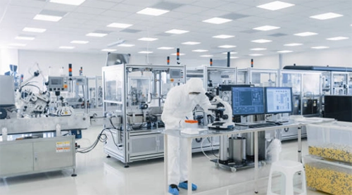 Worker in protective clothing among laboratory equipment.