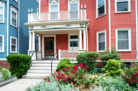 Red clapboard home entrance and landscaping.