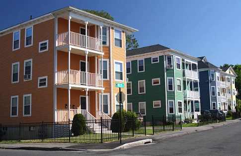 Multi-story clapboard residences with porches along a street.