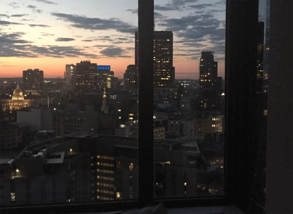 City buildings at sunset, viewed through a window.