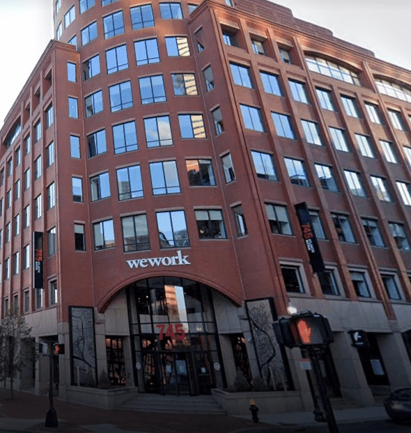Red-brick corner building with a WeWork sign above the entrance.