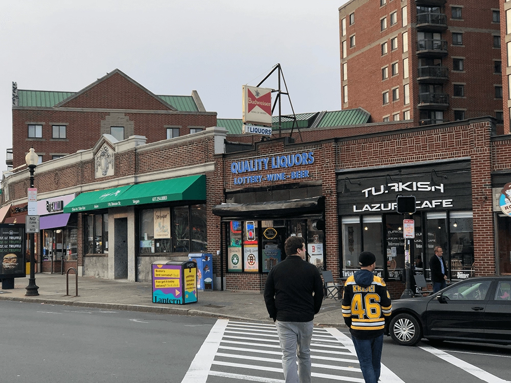 Brick storefronts and pedestrians at a street crossing.