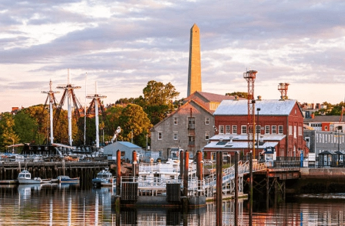 Waterfront buildings and ship masts with an obelisk in the background.