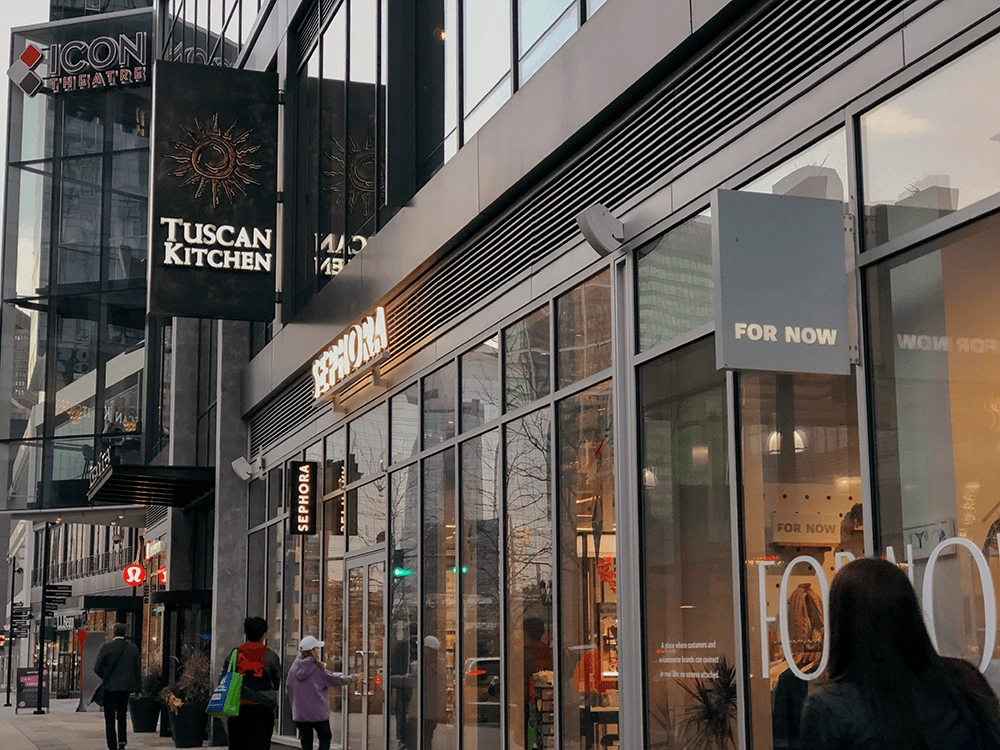 Retail storefronts and pedestrians along a modern commercial street