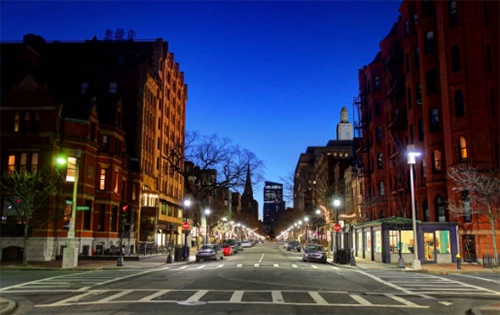 City streetscape at dusk with illuminated storefronts