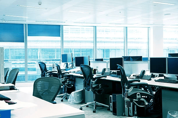 Office desks and computer monitors beside windows