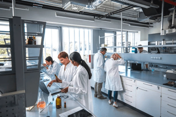 People in lab coats around a laboratory bench