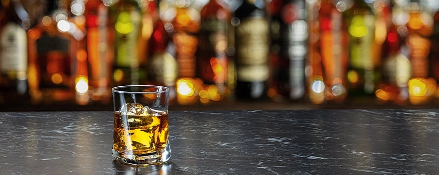 glass of bourbon on bar