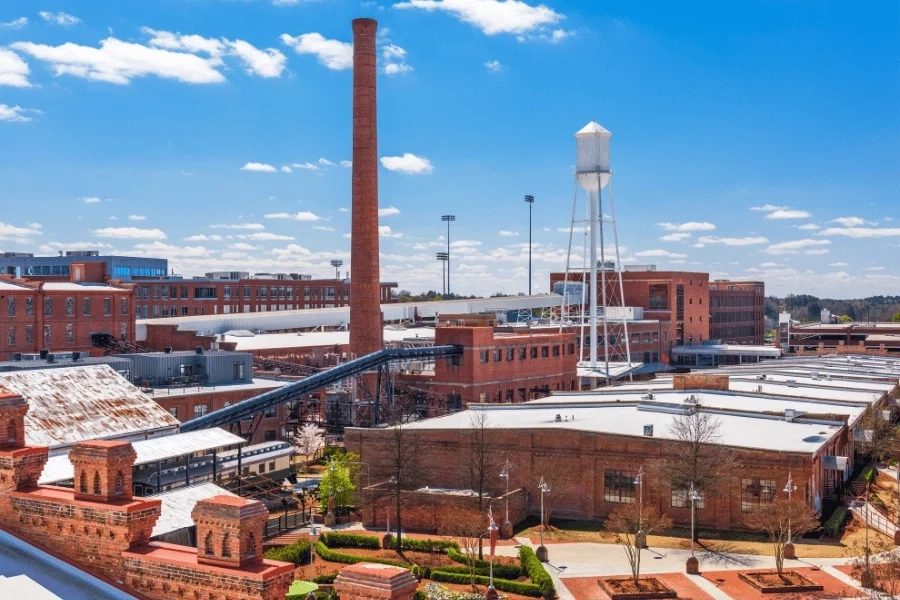 Brick warehouse buildings, a smokestack and a white water tower in Durham. Image courtesy of Raleigh Realty.
