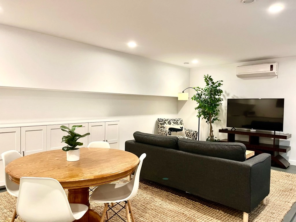 Unit Three — The Garden-Level Retreat Open living and dining area in the garden-level apartment with warm textures and natural light.
