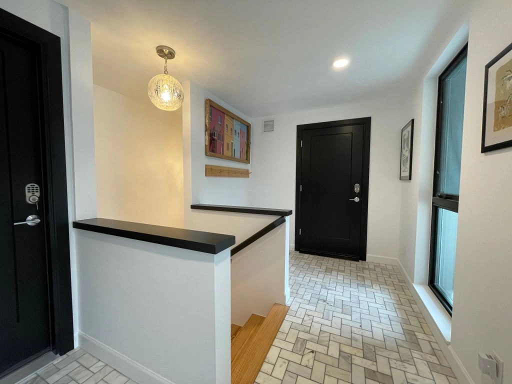 Unit Three — The Garden-Level Retreat Shared foyer in The Denver Longhouse with marble-tiled floors and mercury-glass pendants.