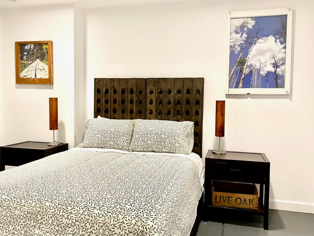 Unit Three — The Garden-Level Retreat Cozy bedroom with large window and neutral decor.
