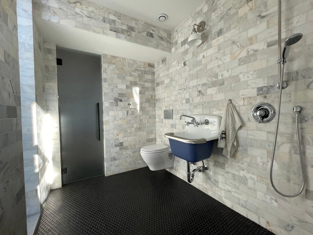 European-style wet room guest bathroom with marble tiles and oversized wash sink.