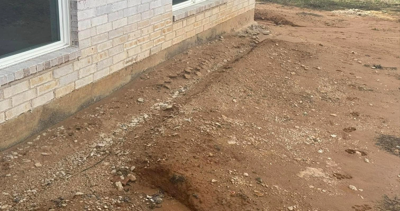 Soil erosion and poor drainage next to a brick home foundation