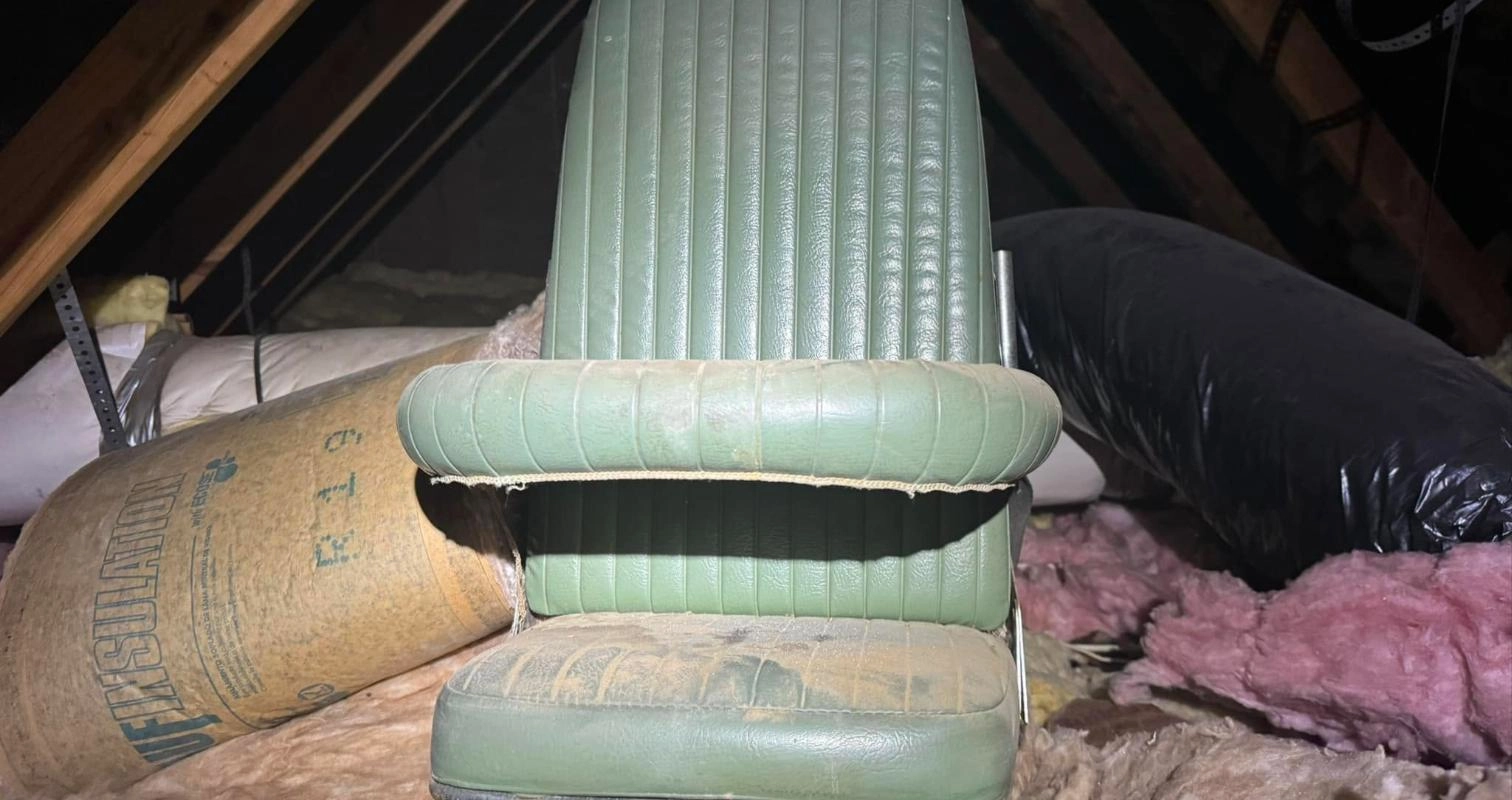 Old vehicle seat sitting on attic insulation found during a home inspection