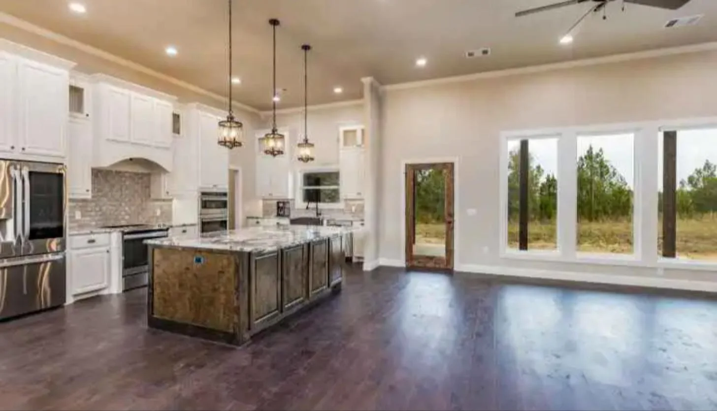 Open-concept kitchen with large island, pendant lights and white cabinets in a custom home by Ward Construction