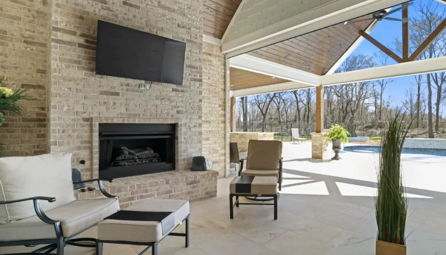 Covered outdoor living area with brick fireplace, cedar vaulted ceiling and pool view built by Ward Construction