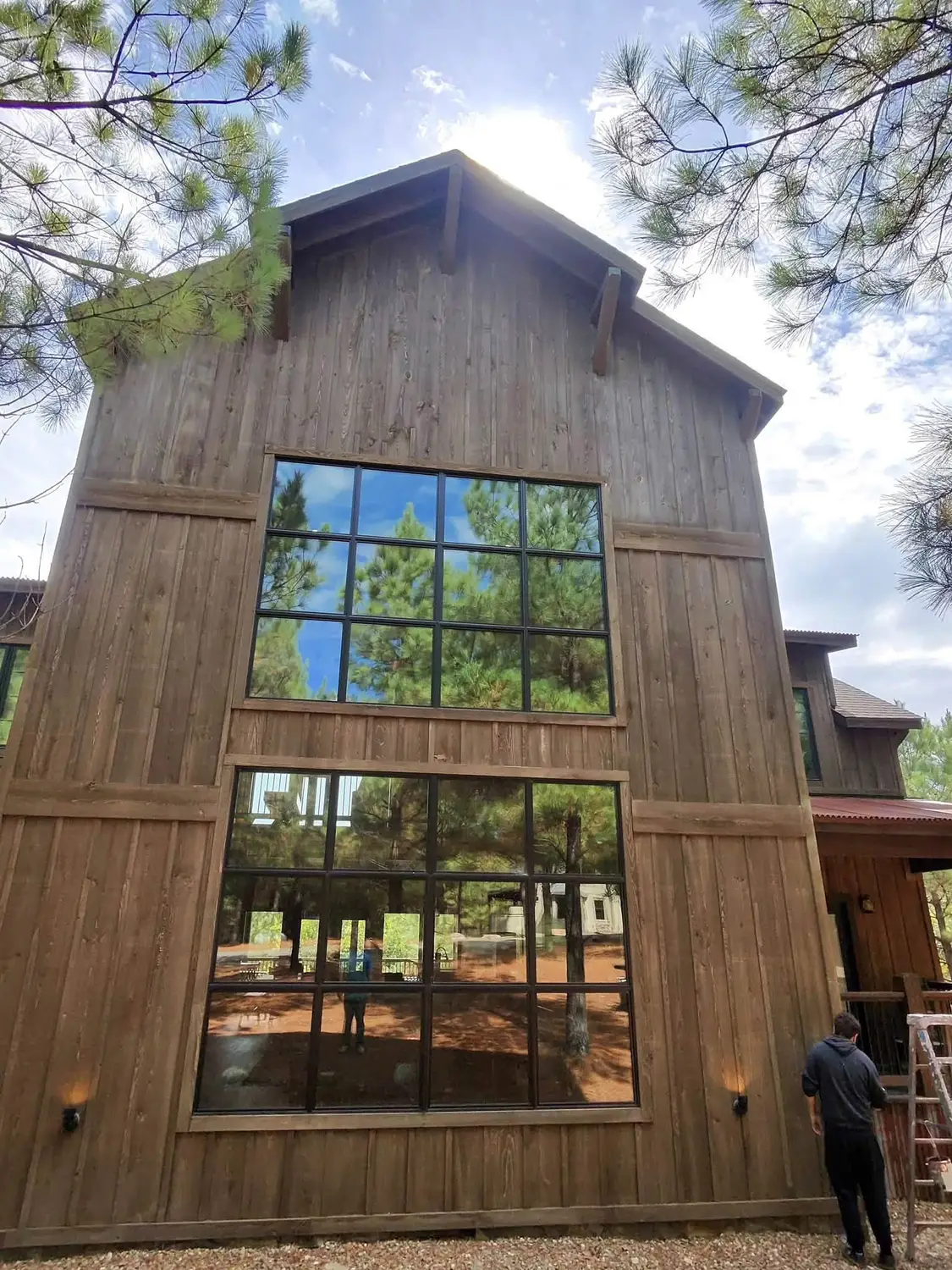 Large wood cabin with tall windows being stained by Brush and Roller in Hochatown, Oklahoma