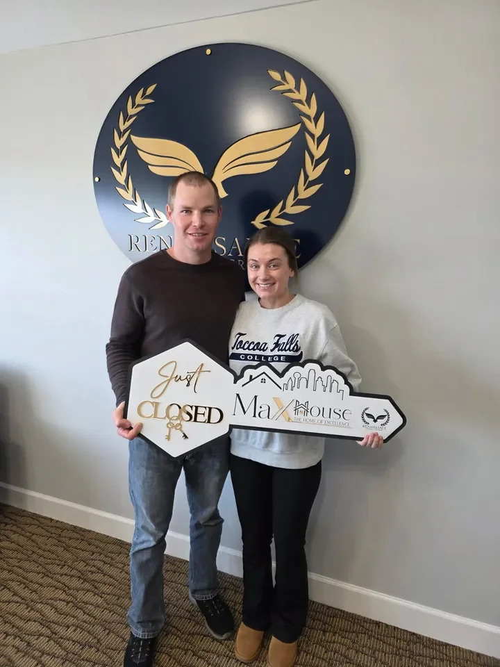 Two people celebrating a closing with a MaX House key sign.