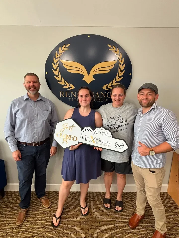 Four people gathered with a Just Closed sign at the title office.