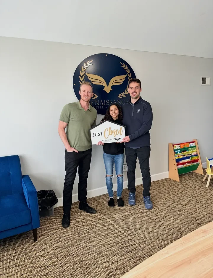 Three people smiling with a Just Closed sign.