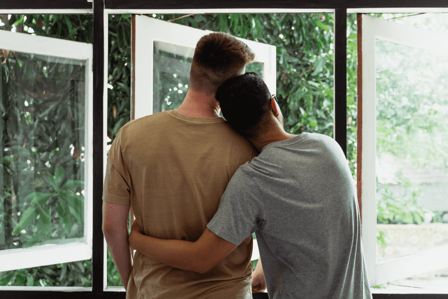 A couple staring out window of their home.