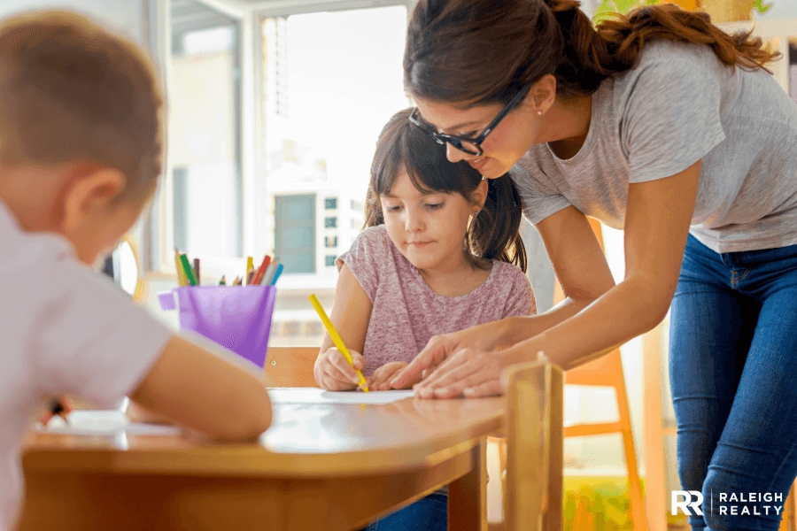 Teacher showing kids in classroom how to accomplish things in their workbook