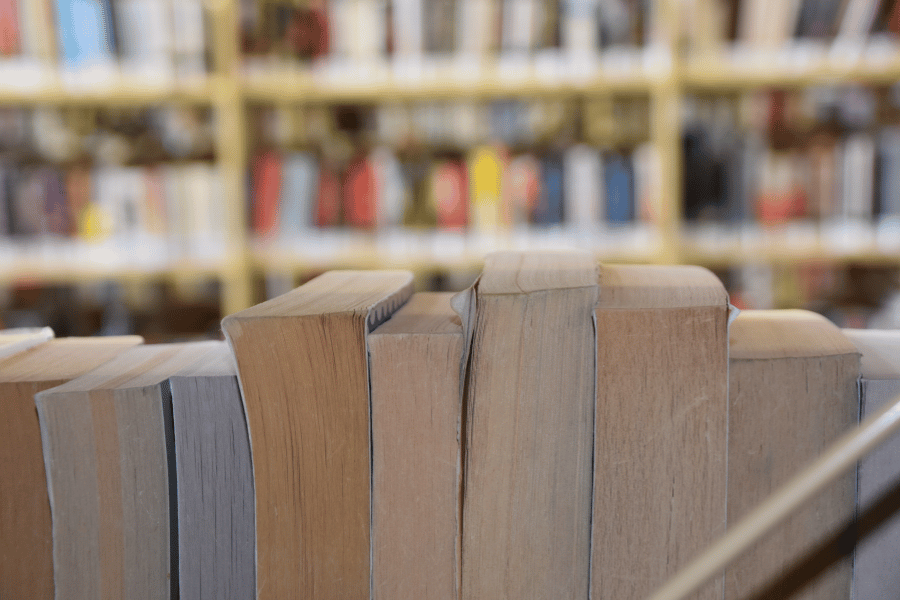 paperback books lined up on a shelf at the library 