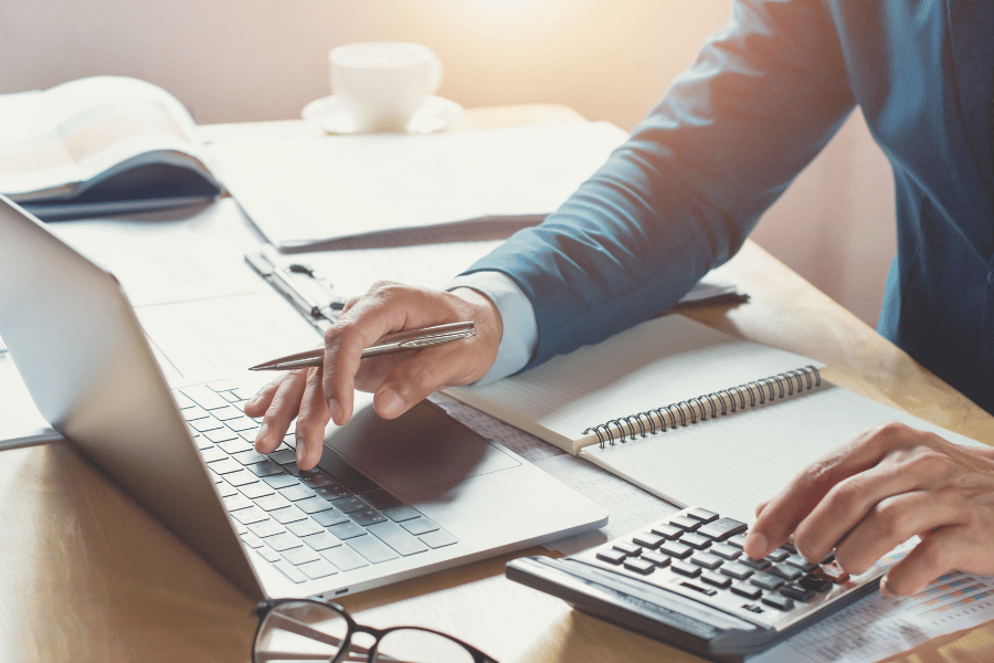homeowner working on taxes at home with calculator and computer