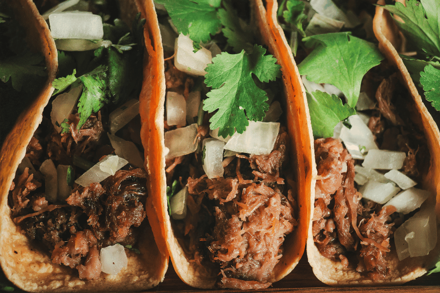 three tacos with onion and cilantro