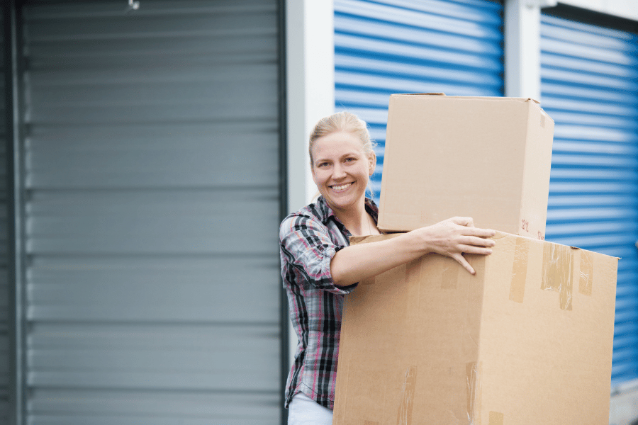 happy customer at a storage facility carrying boxes of items 