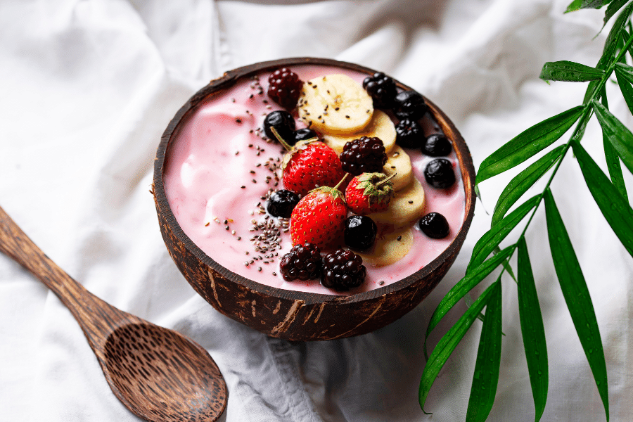 Acai bowl with fruit and wood spoon on a white background