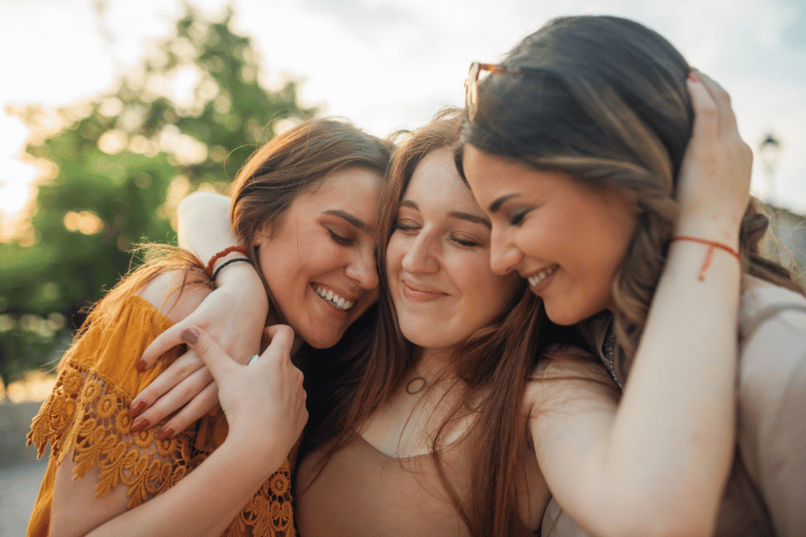three friends smiling and hugging goodbye 