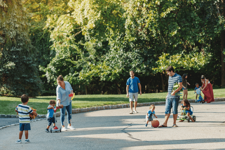 neighbors with kids playing in the street on a sunny day