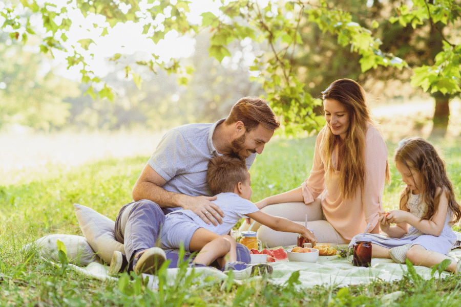 dParents and young kids enjoying a family picnic outside on a nice day