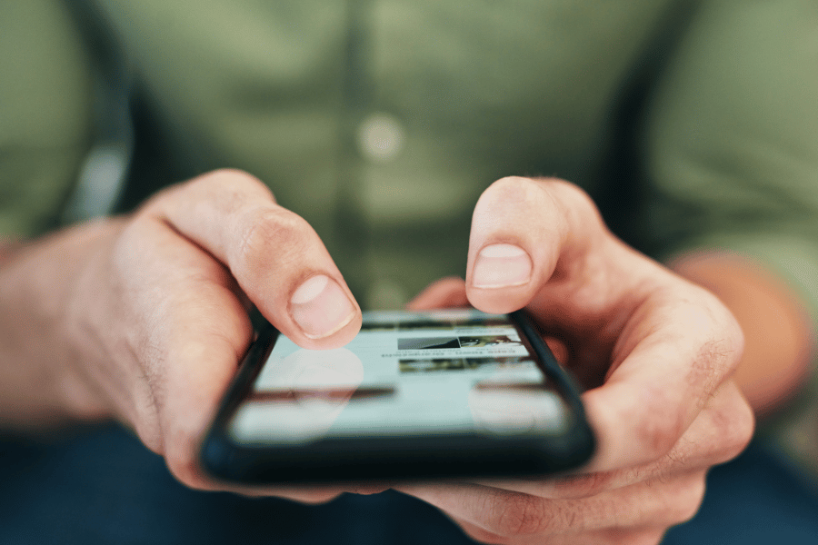 man in a green shirt sitting down on his phone and using social media