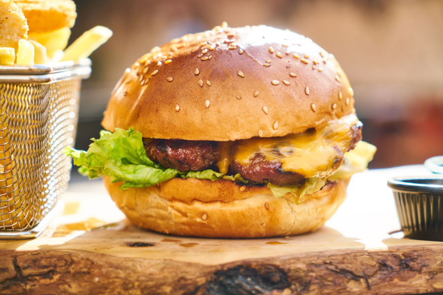 Hamburger on with lettuce on wood slab with french fries
