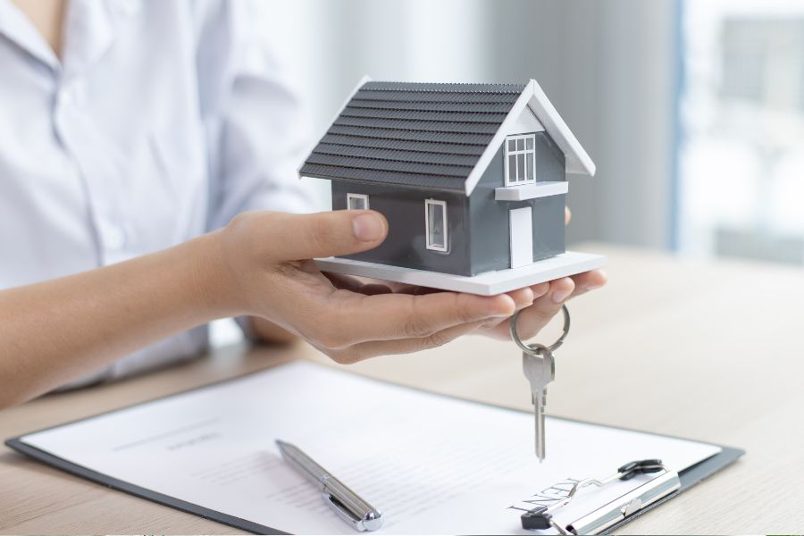 Photo of gray house and key in hands